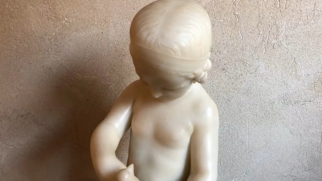 antique sculpture of a child holding a bird