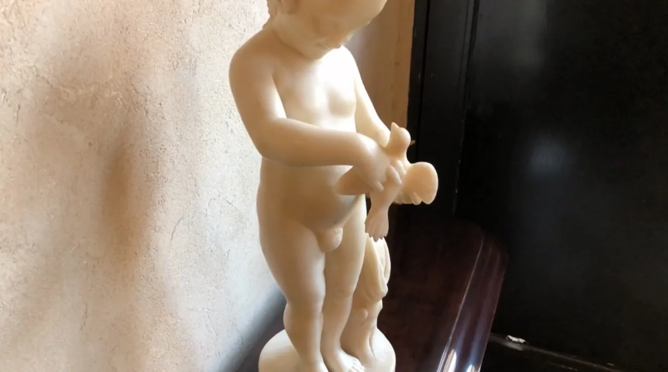 escultura antigua de un niño sosteniendo un pájaro