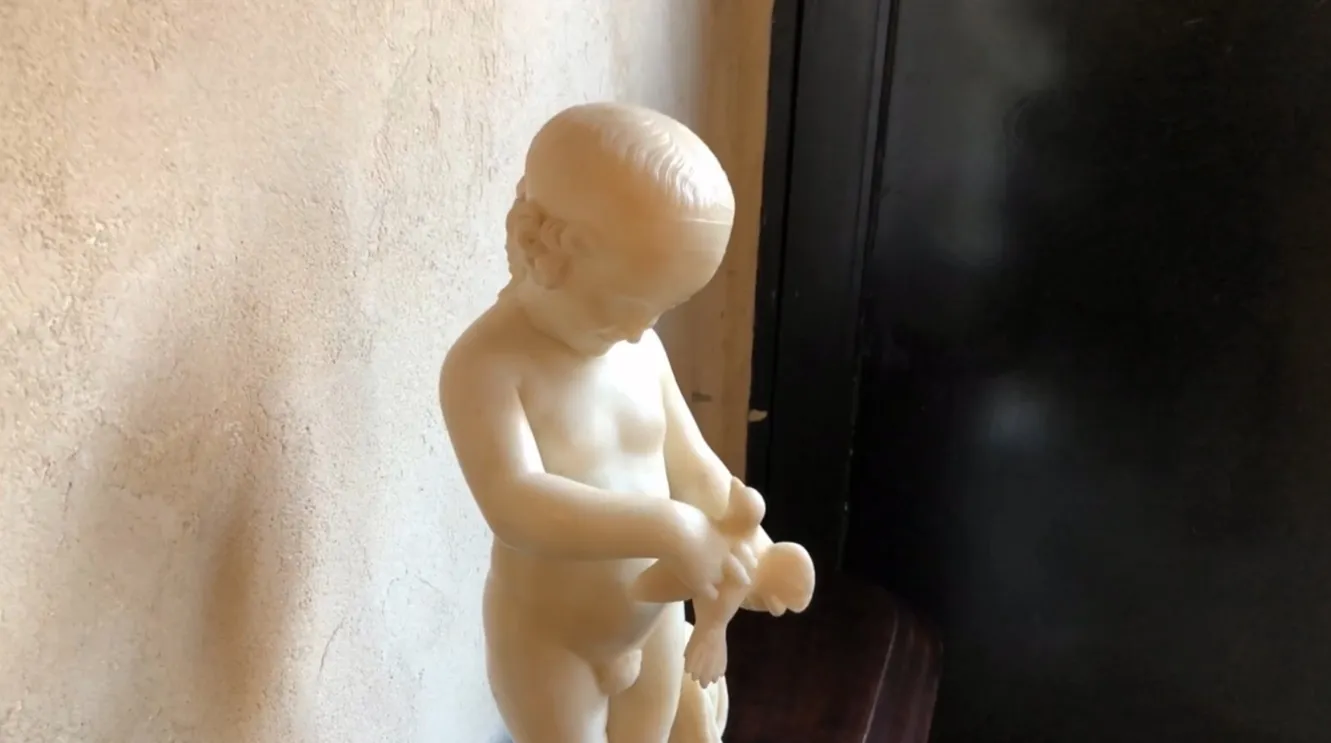 antique sculpture of a child holding a bird