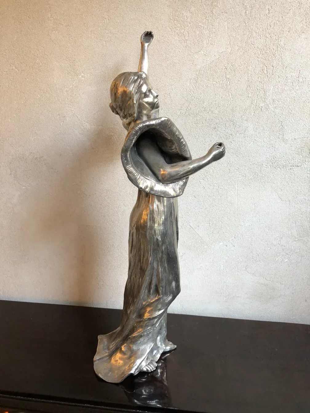 ancient sculpture of female figure raising arms