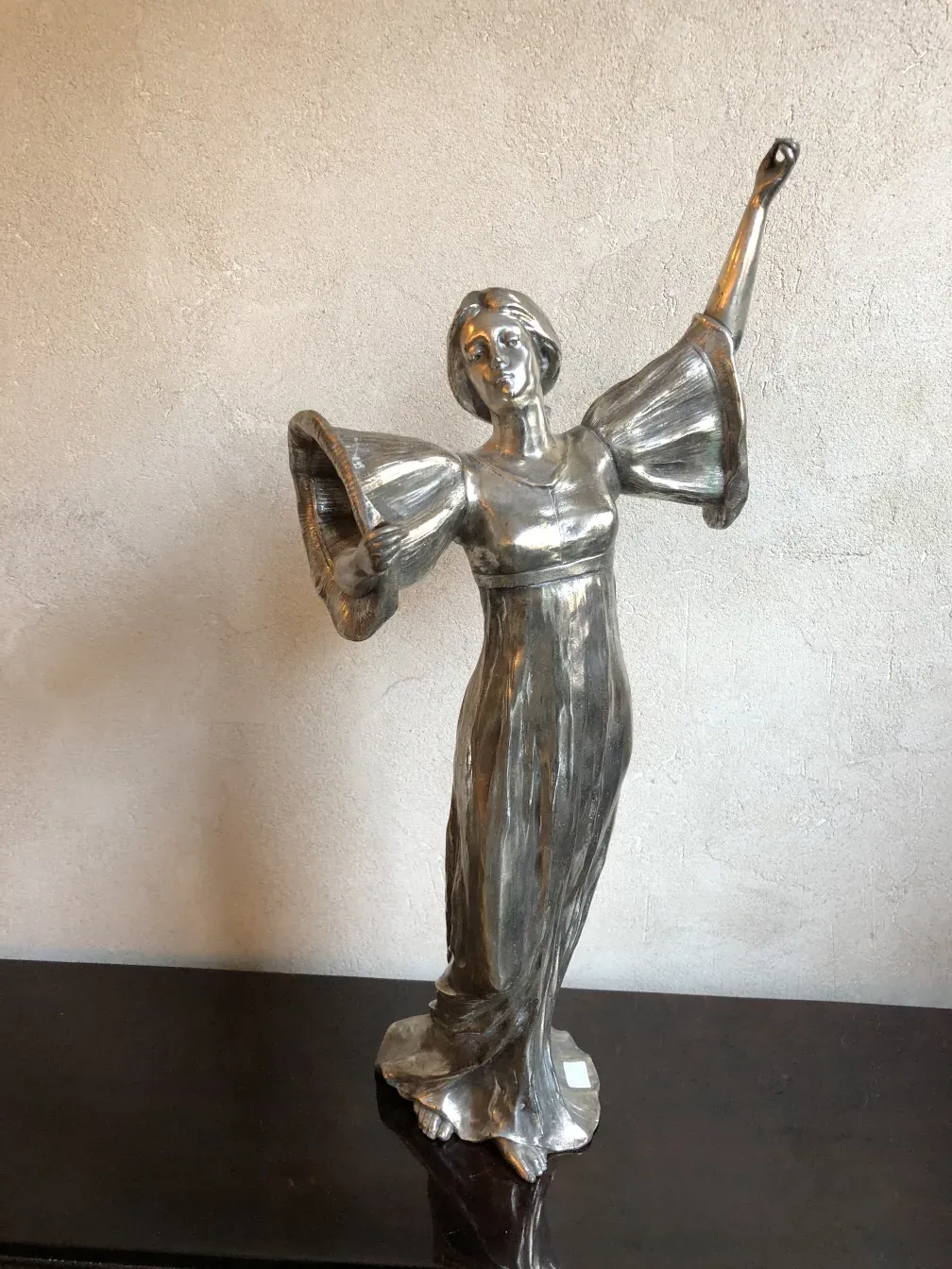 ancient sculpture of female figure with arms raised