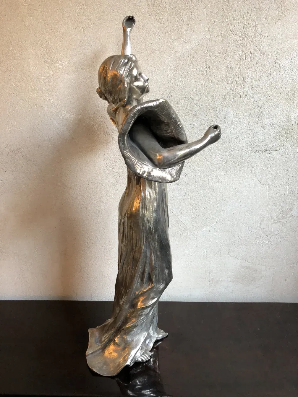 escultura antigua de figura femenina elevada con brazos en alto, detalles sutiles