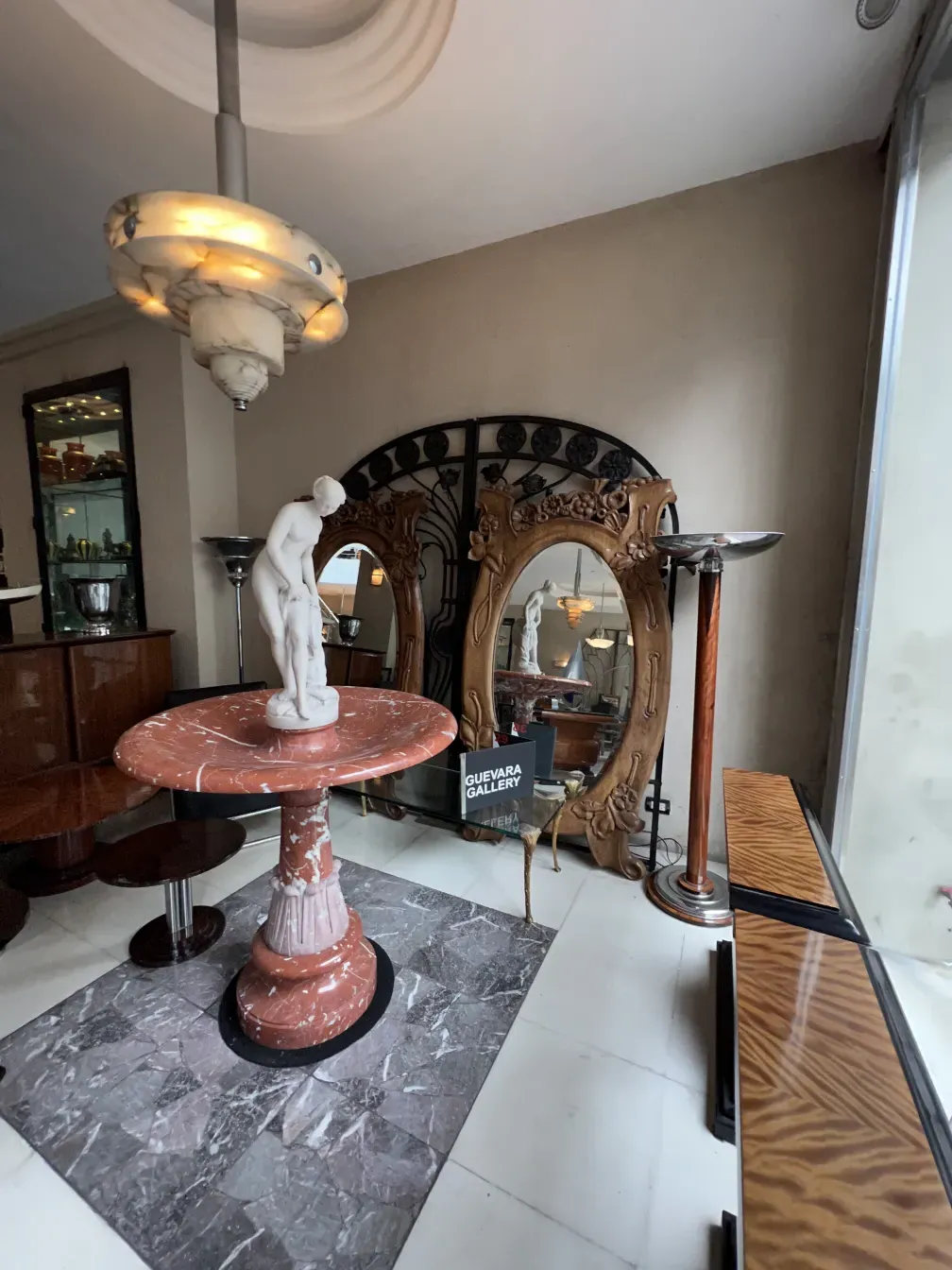 Antique pink marble fountain with a central figure and decorative mirror.