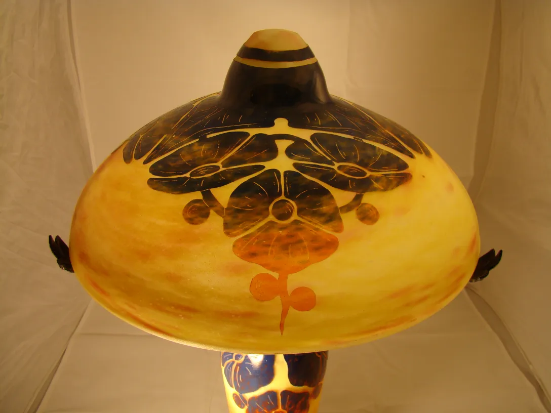 Lâmpada de vidro decorativa com design floral em tons de marrom e amarelo.