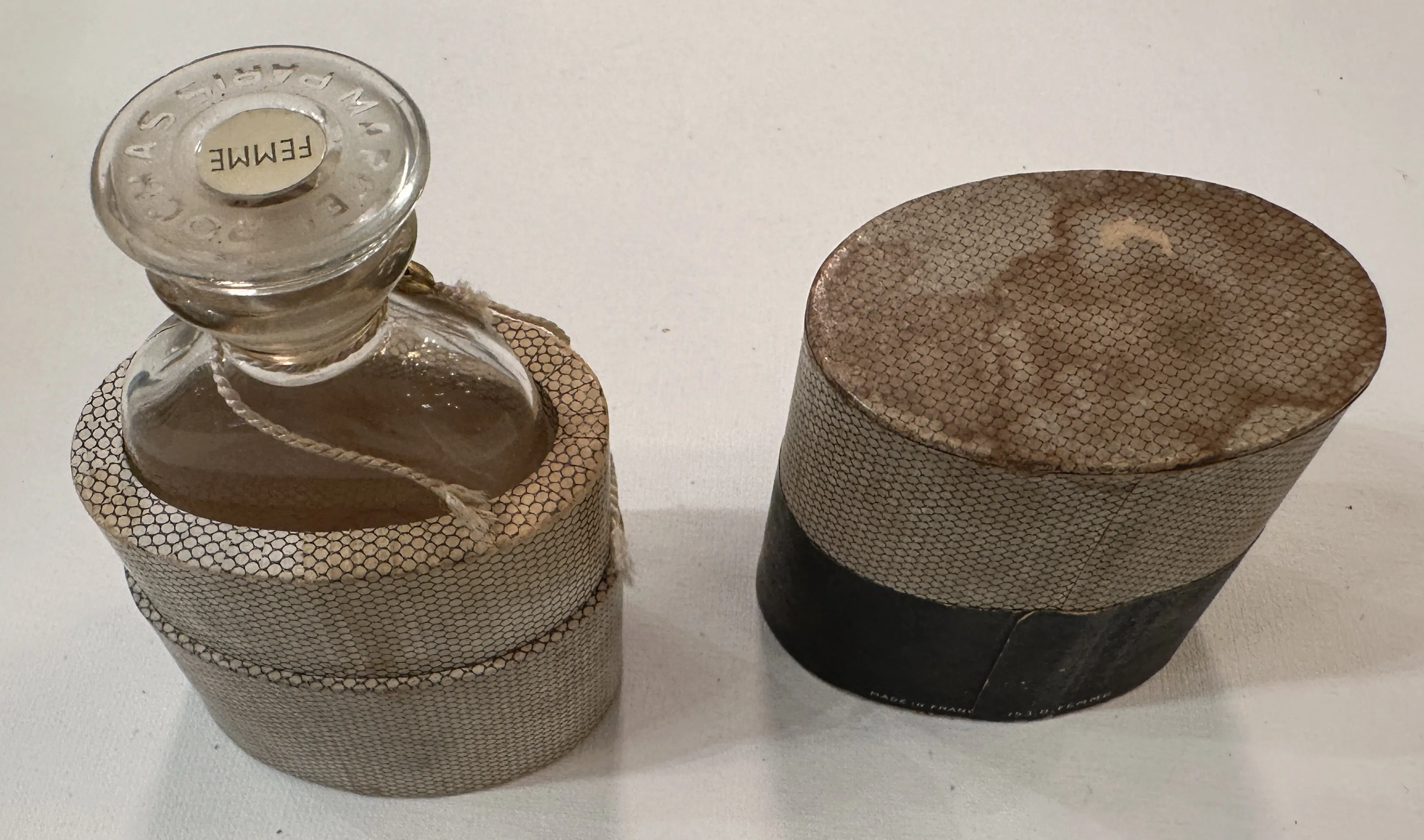 Antike Parfümflasche mit dekorativem Deckel, in einer neutralen Umgebung präsentiert.