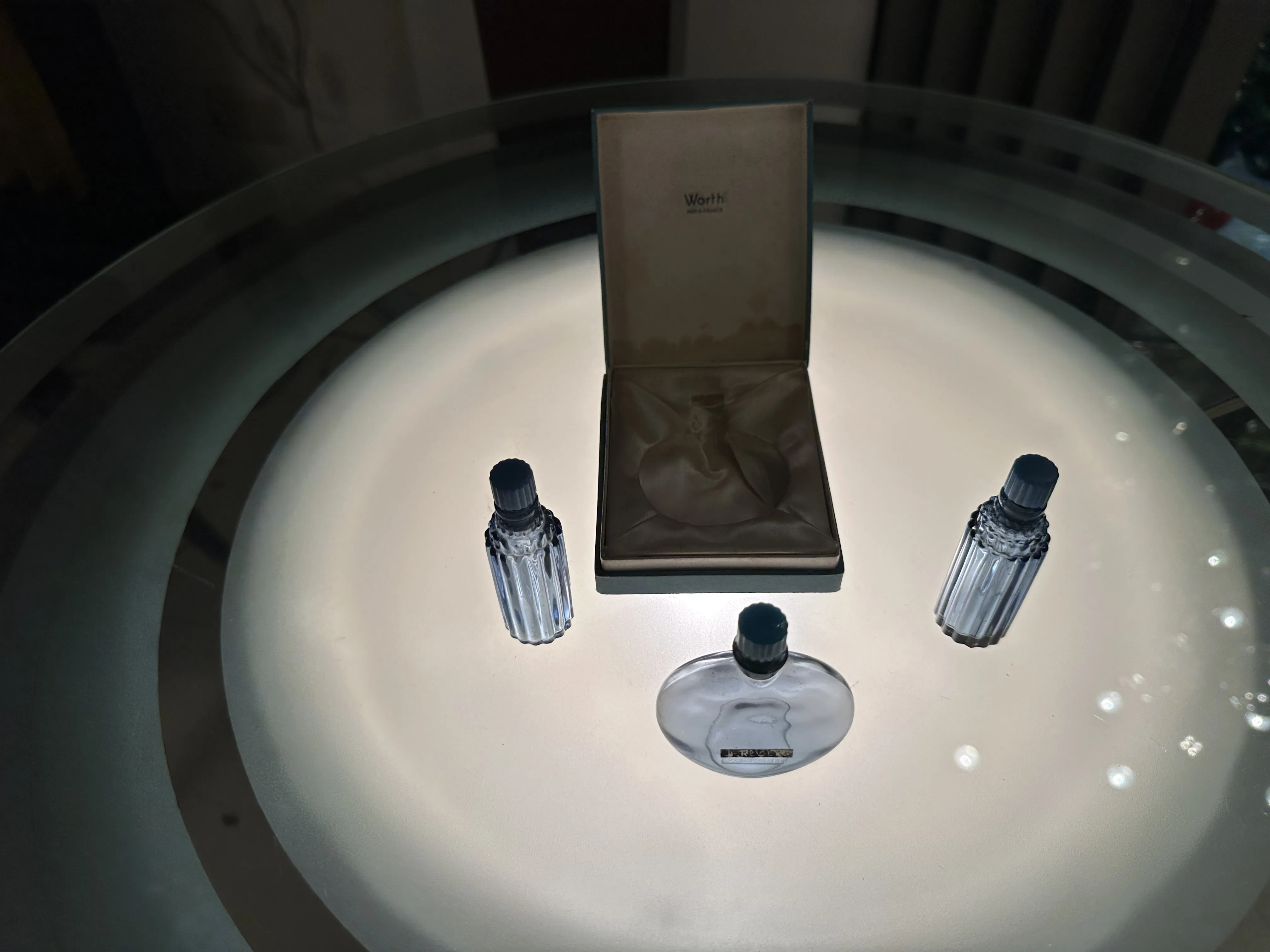 ثلاث زجاجات عطر قديمة على طاولة مضاءة