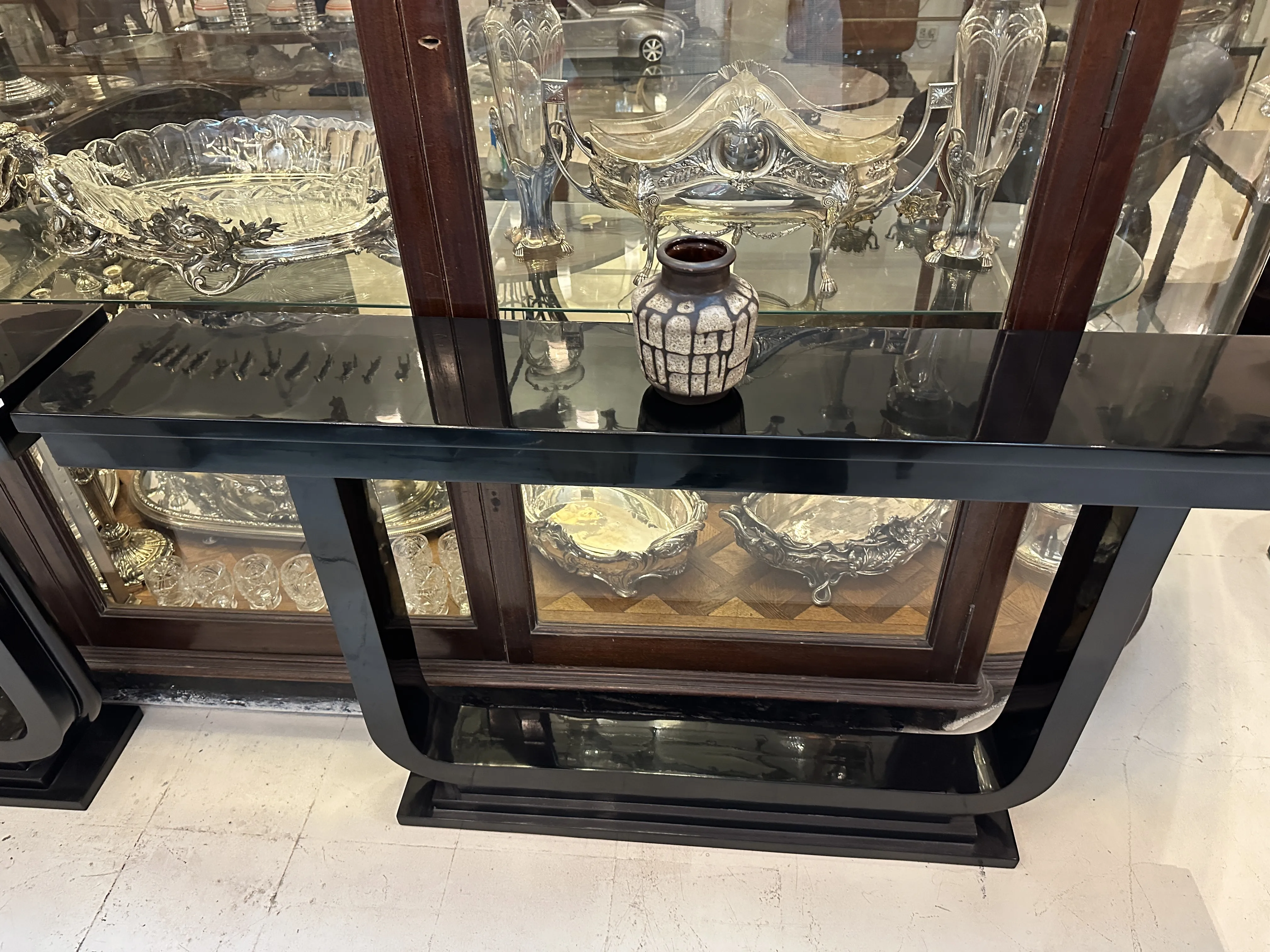 Antique decorative ceramic on display with silver items. Dark, geometric vase.