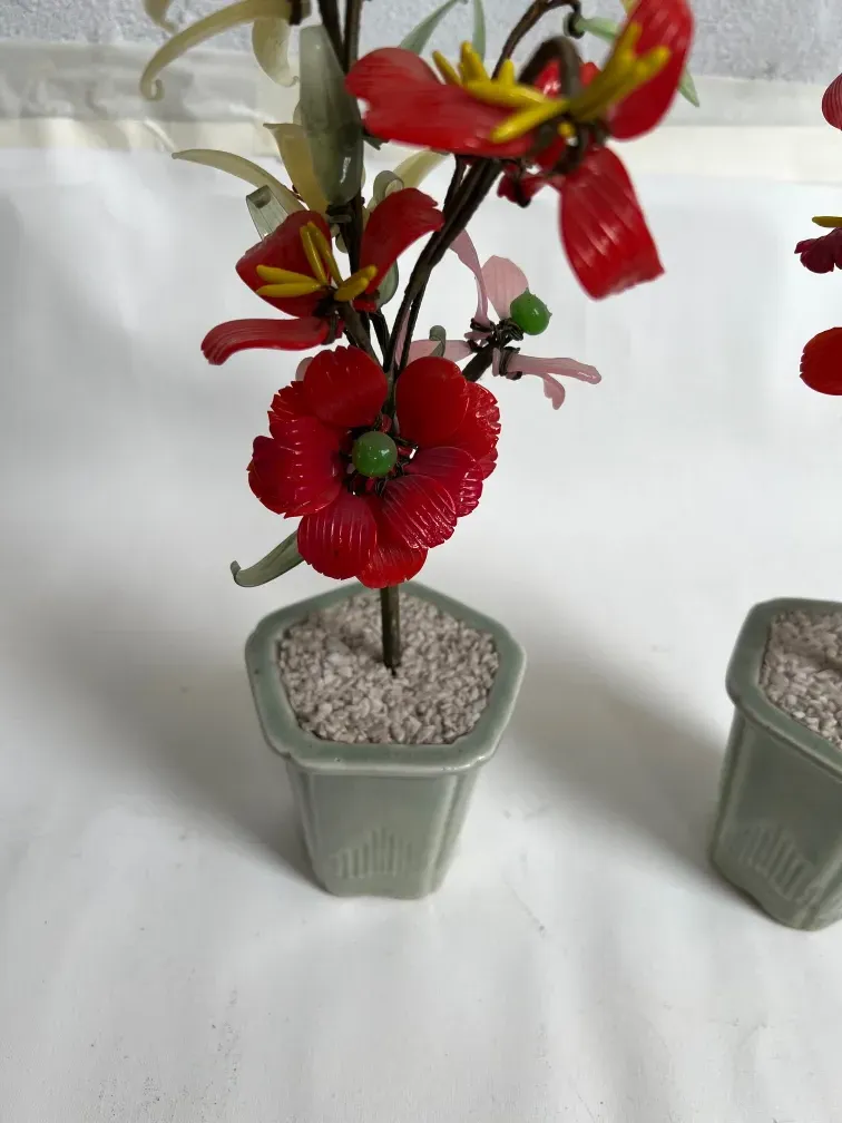 Bonsái antiguo con flores rojas y maceta decorativa