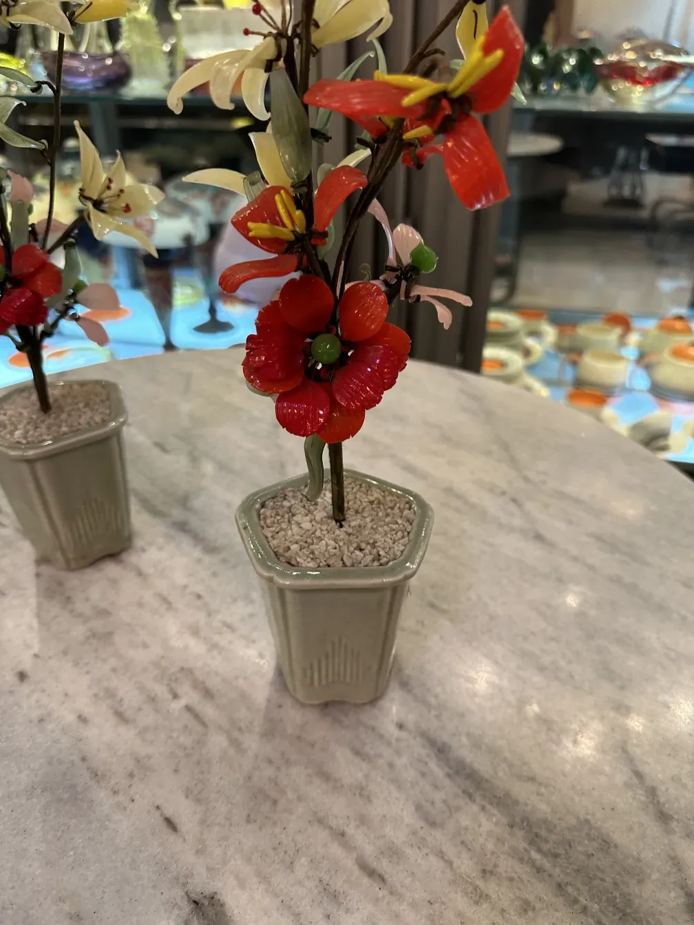 Bonsai antigo com flores vermelhas e amarelas em vaso de cerâmica.
