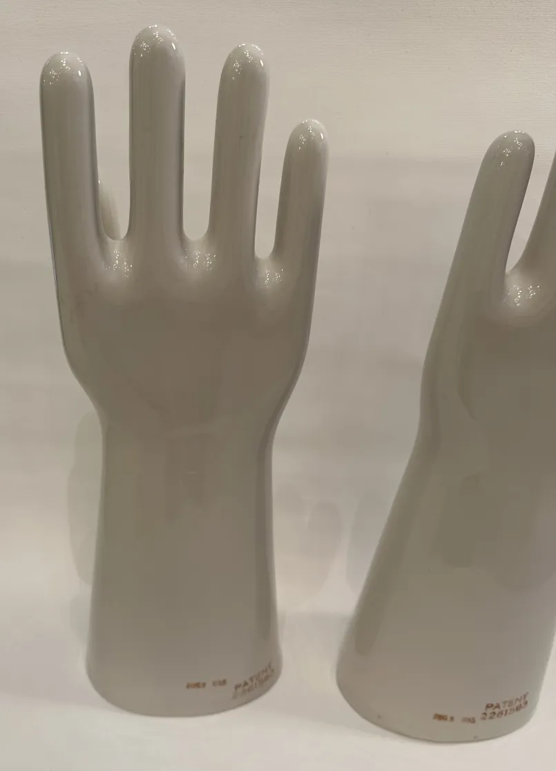 Par de mãos de cerâmica, antigas e brilhantes, mostrando detalhes da forma em um ambiente neutro.