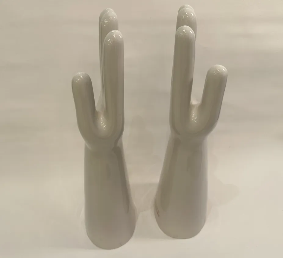 Paire de mains en céramique, anciennes et brillantes, présentant des détails de la forme dans un cadre neutre.