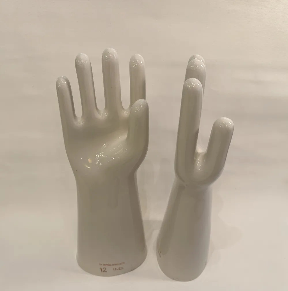 Par de mãos de cerâmica, antigas e brilhantes, mostrando detalhes da forma em um ambiente neutro.