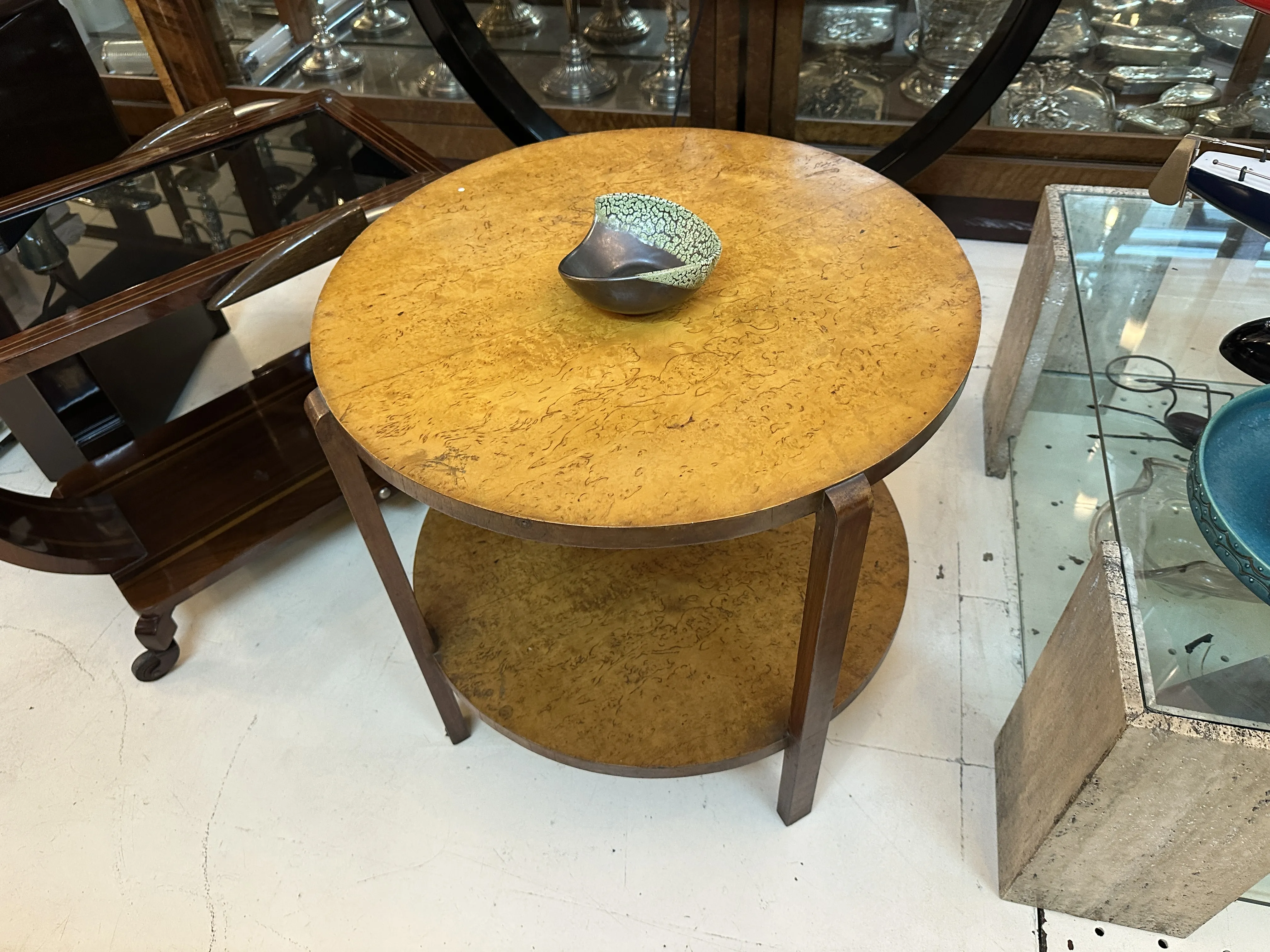 Mesa redonda de madeira com uma peça de cerâmica em cima, em um ambiente antigo e aconchegante.