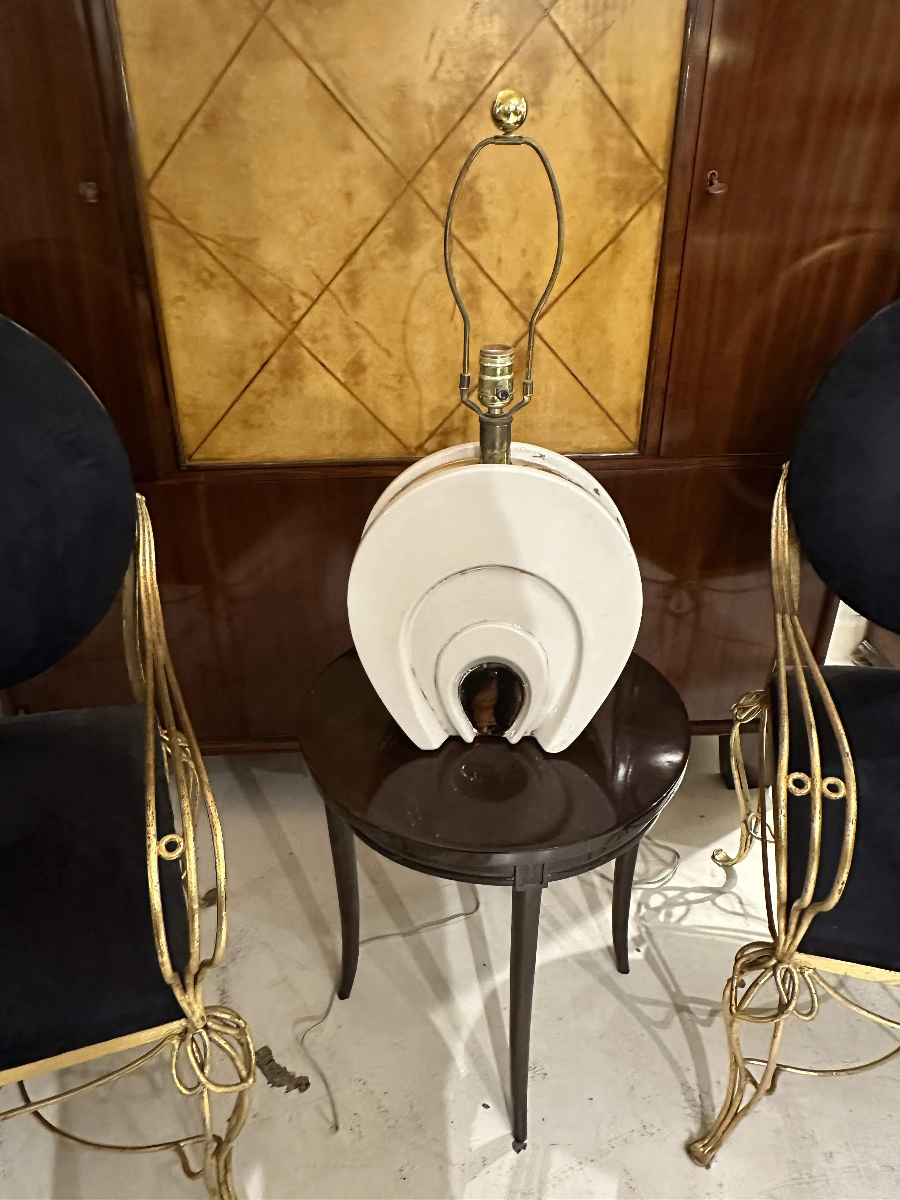 Ancienne lampe de bureau avec une base au design unique et des détails subtils, dans un cadre élégant avec des chaises décoratives.
