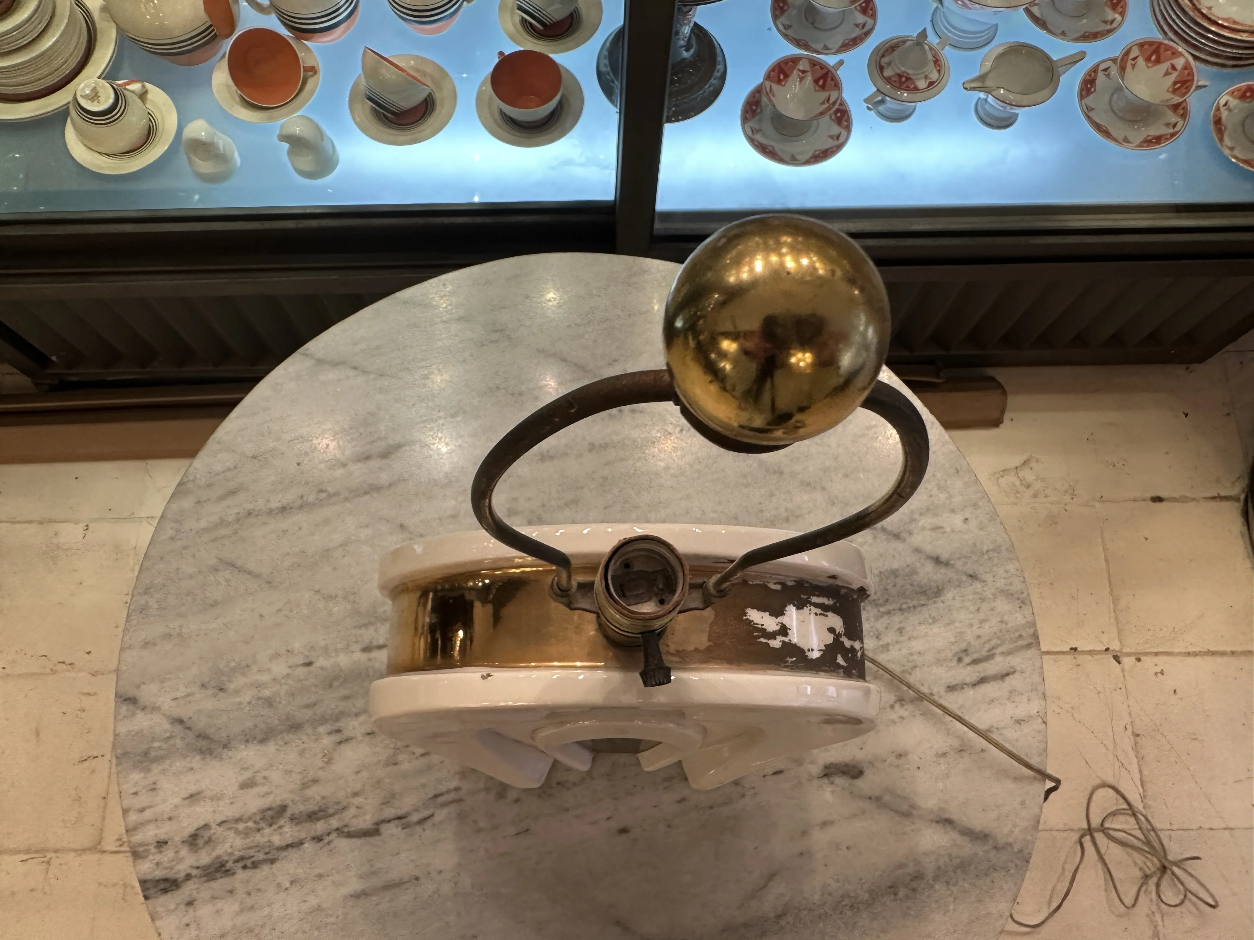 Lampe de bureau ancienne avec base blanche et sphère dorée, dans un cadre ancien.