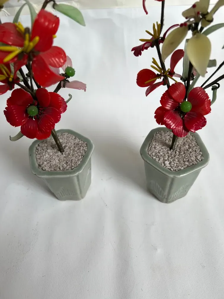 Bonsái antiguo con flores rojas y verdes en macetas