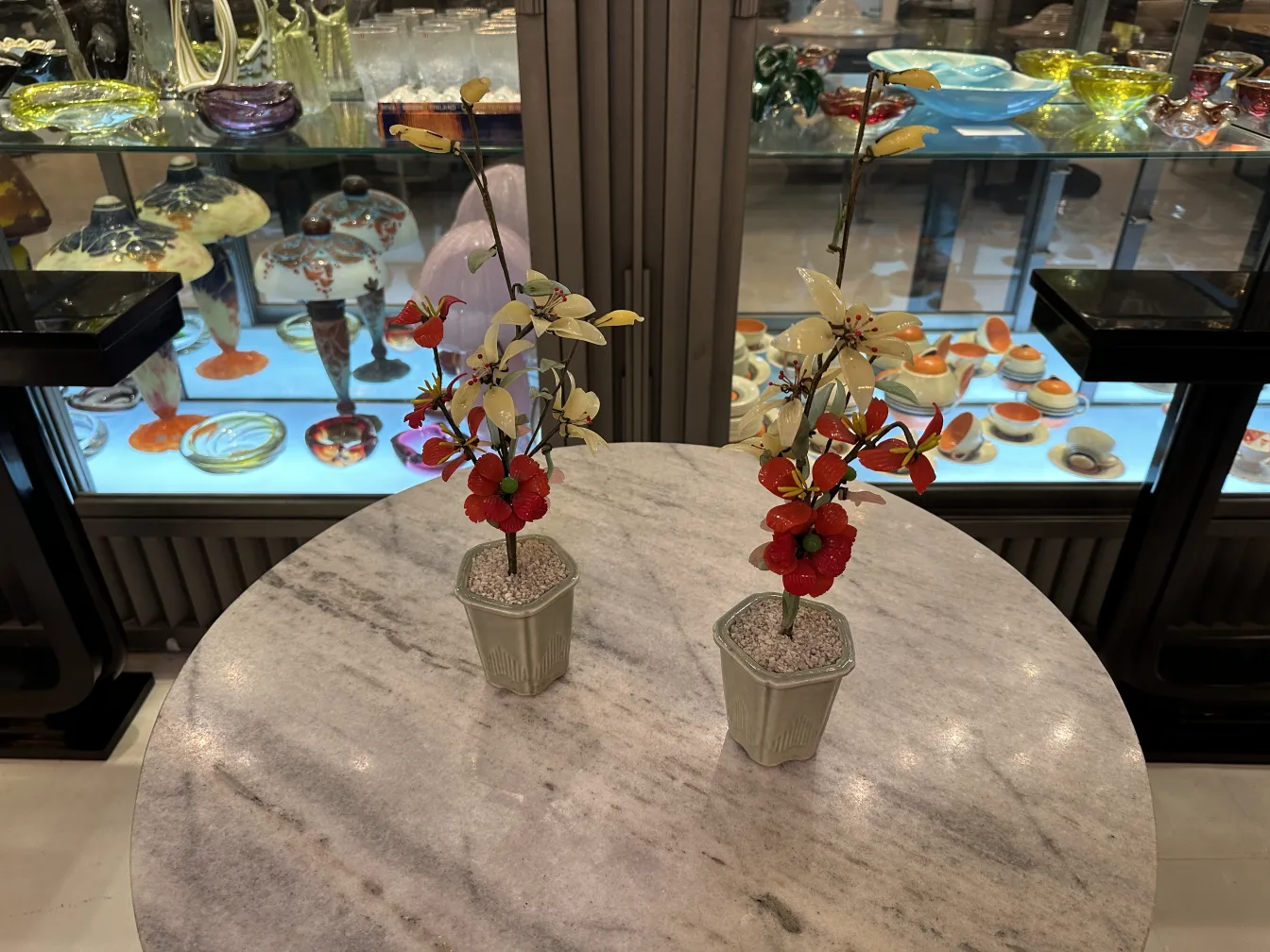 Bonsai antigo com flores vermelhas e brancas em vaso decorativo, ambiente elegante.