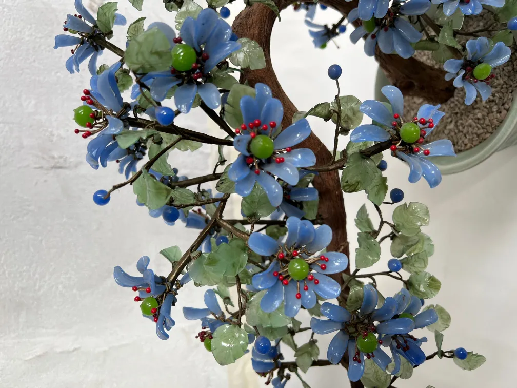Bonsai ancien avec des fleurs bleues et vertes éclatantes.