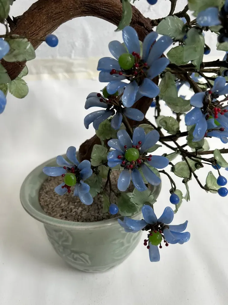 antiker bonsai mit blauen blumen und dekorativen grünen blättern