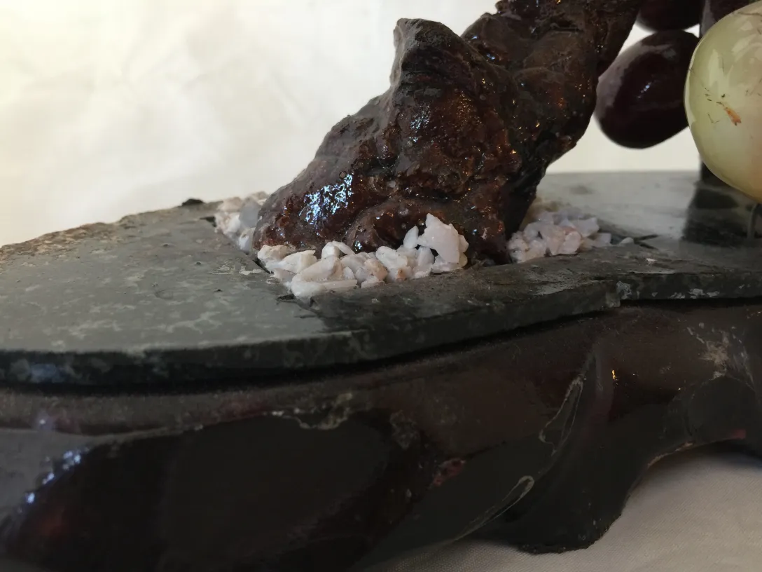 Bonsái en base negra con piedras blancas y fondo neutral