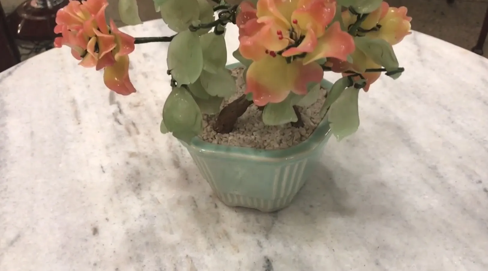 Schöner antiker Bonsai mit orange-grünen Blüten in einem Keramiktopf.