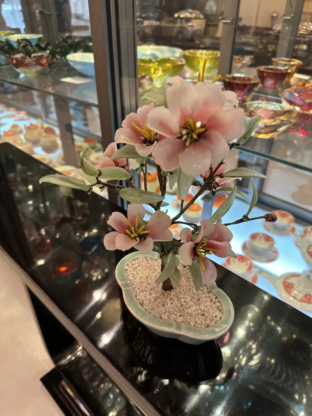 古い盆栽にはピンクの花と緑の葉がある。