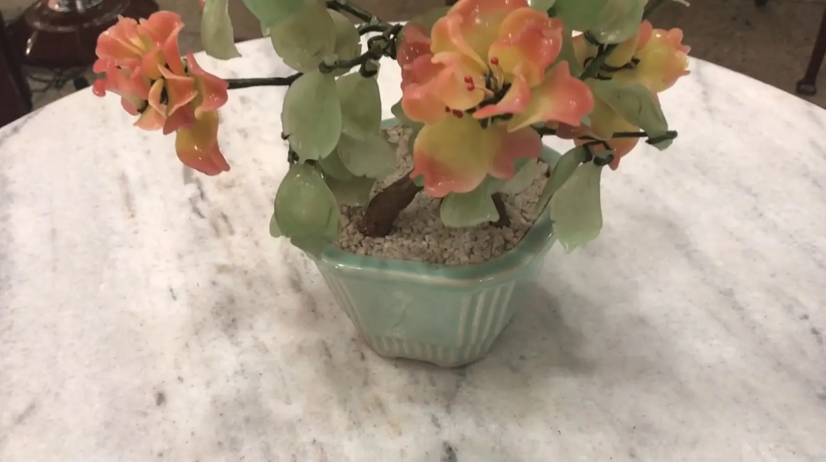 Bonsái antiguo con flores de colores en una maceta decorativa.