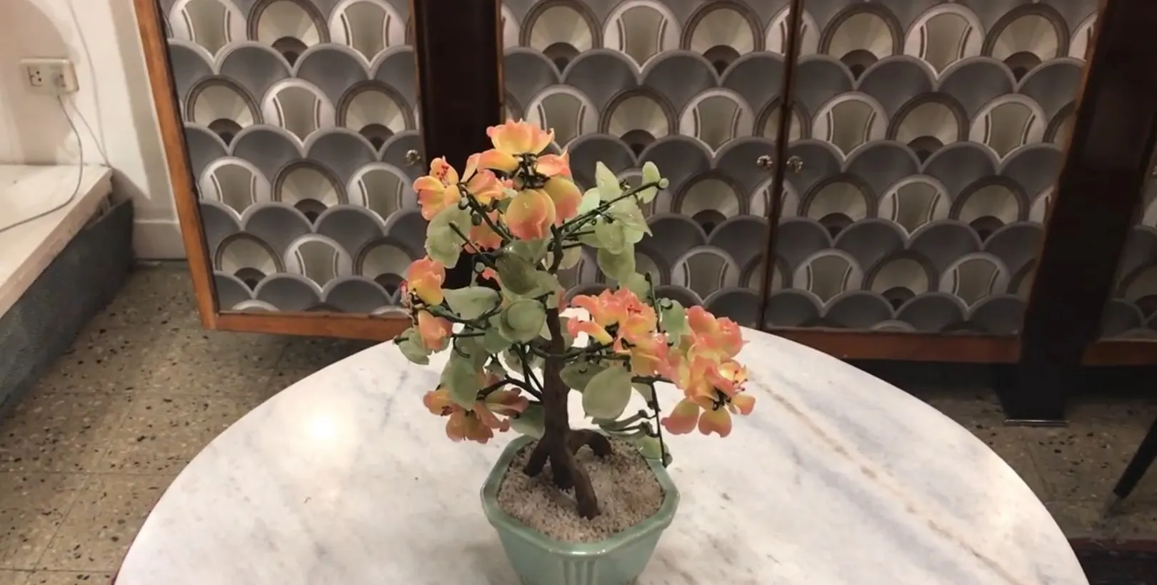 Antiker Bonsai in einem grünen Topf mit rosa Blumen gepflanzt.