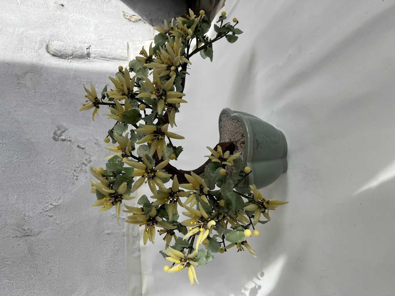 Bonsai antigo com flores amarelas em vaso verde.