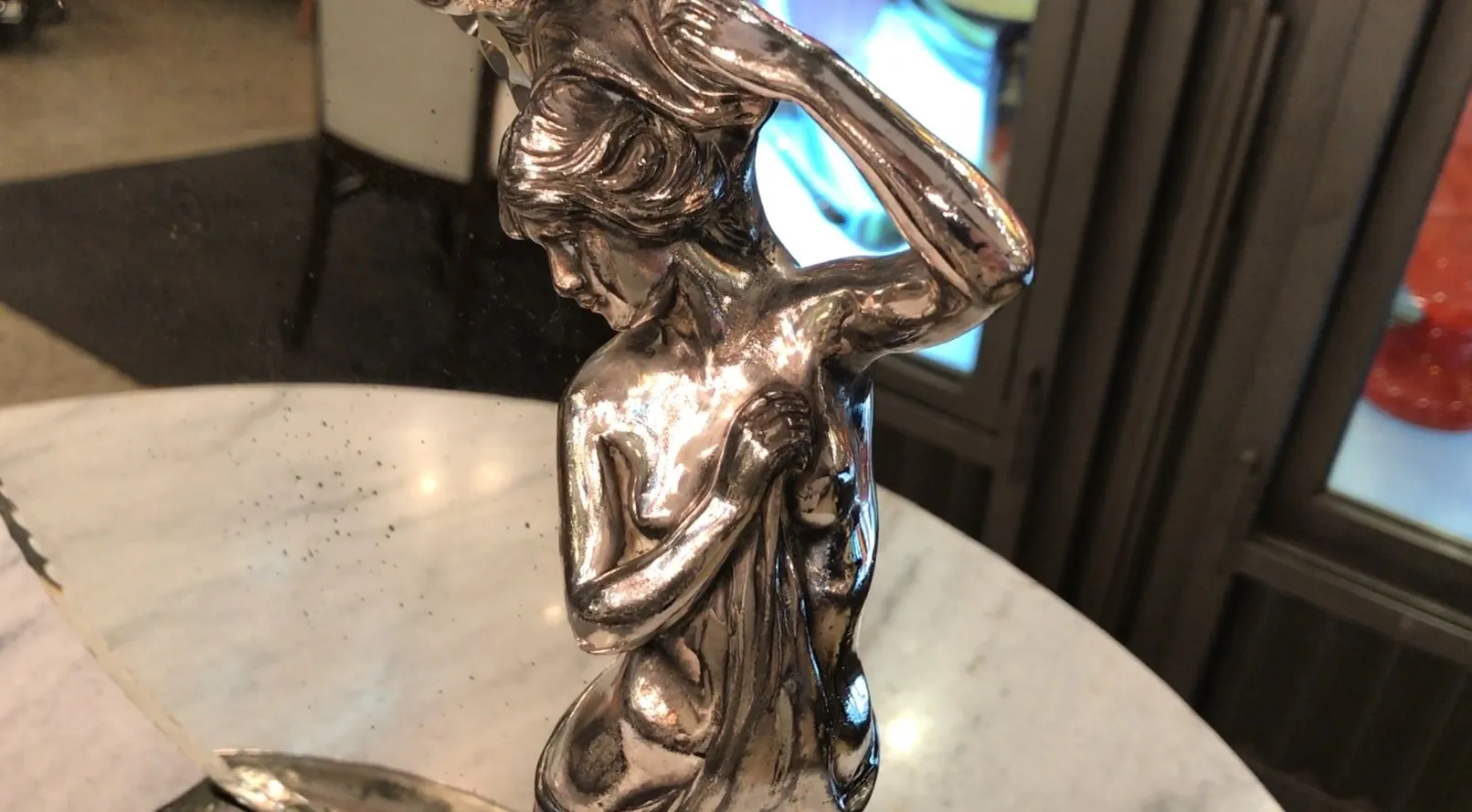 古董镜子，带有装饰底座和女性雕像，反射在大理石上
