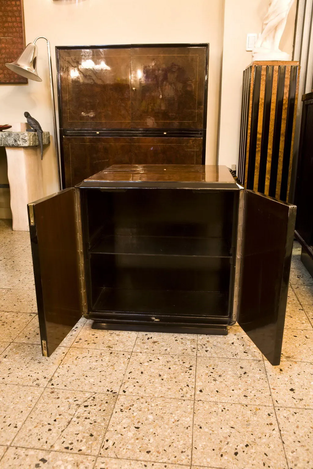 Meuble à cocktail ancien avec portes ouvertes, intérieur sombre et ambiance chaleureuse.