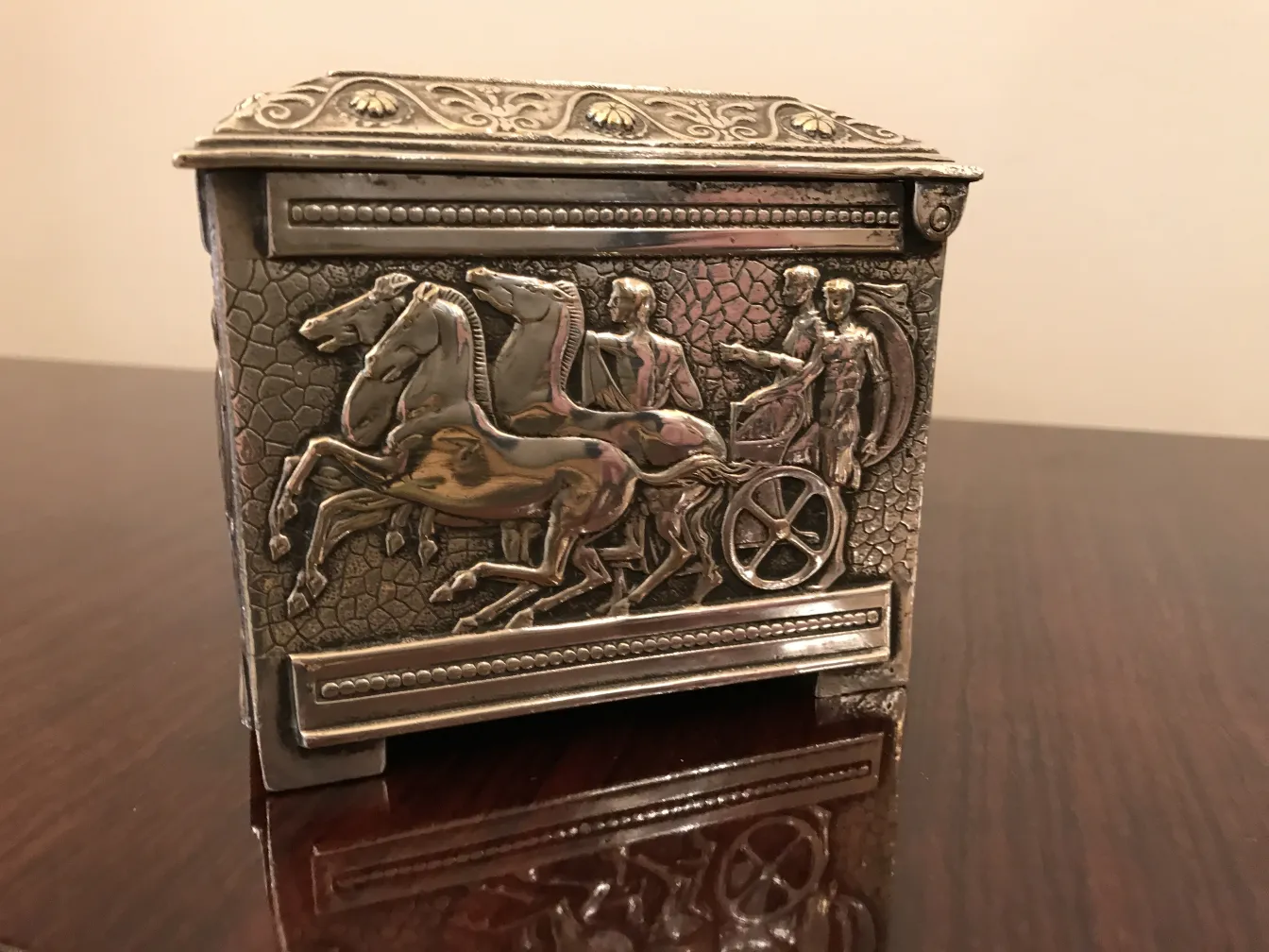 Caixa antiga decorada com uma cena de cavalos em movimento.