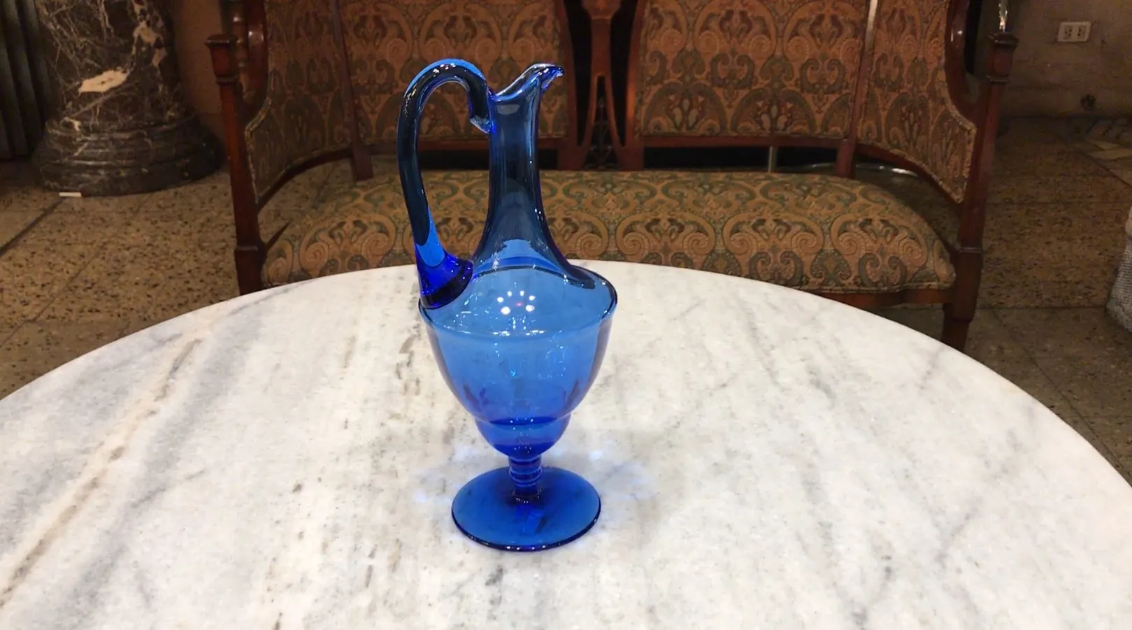 jarra antigua de cristal azul sobre una mesa de mármol