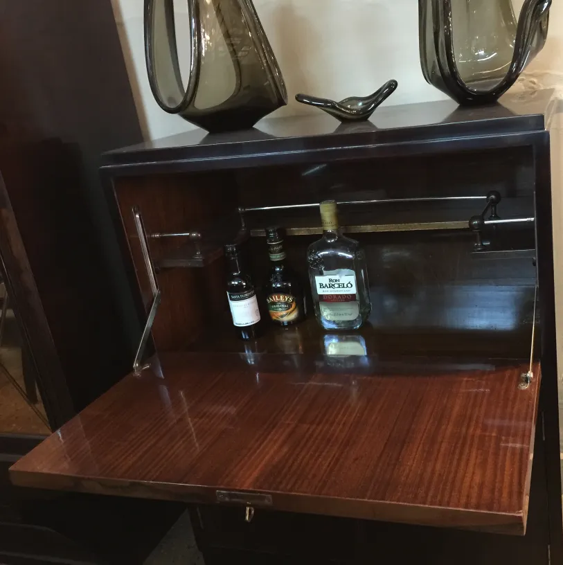 Antikes Bar-Möbel mit Holzoberfläche und sichtbaren Flaschen, dekoriert mit eleganten Objekten.