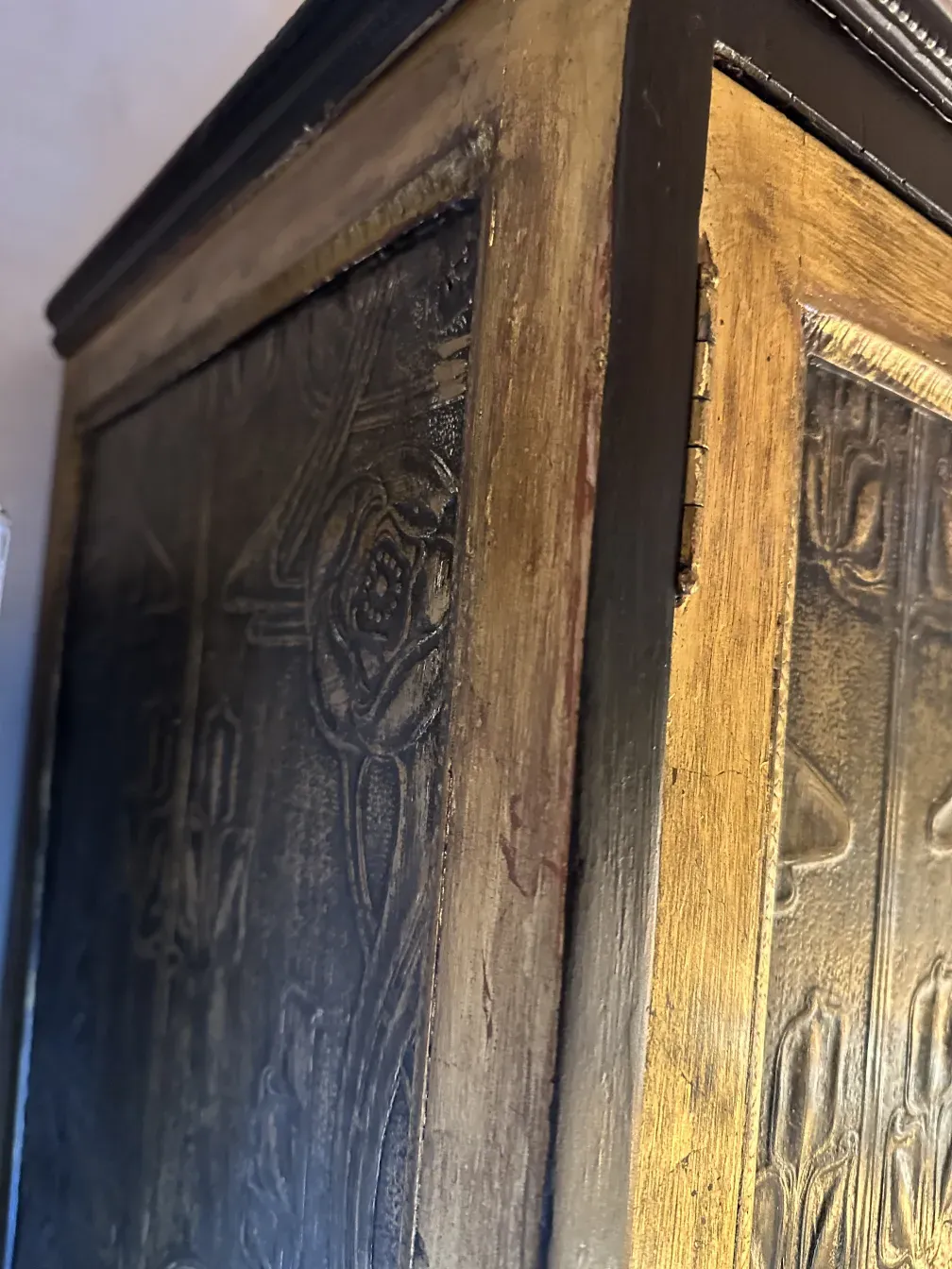 Mueble bar antiguo con relieves y detalles dorados.