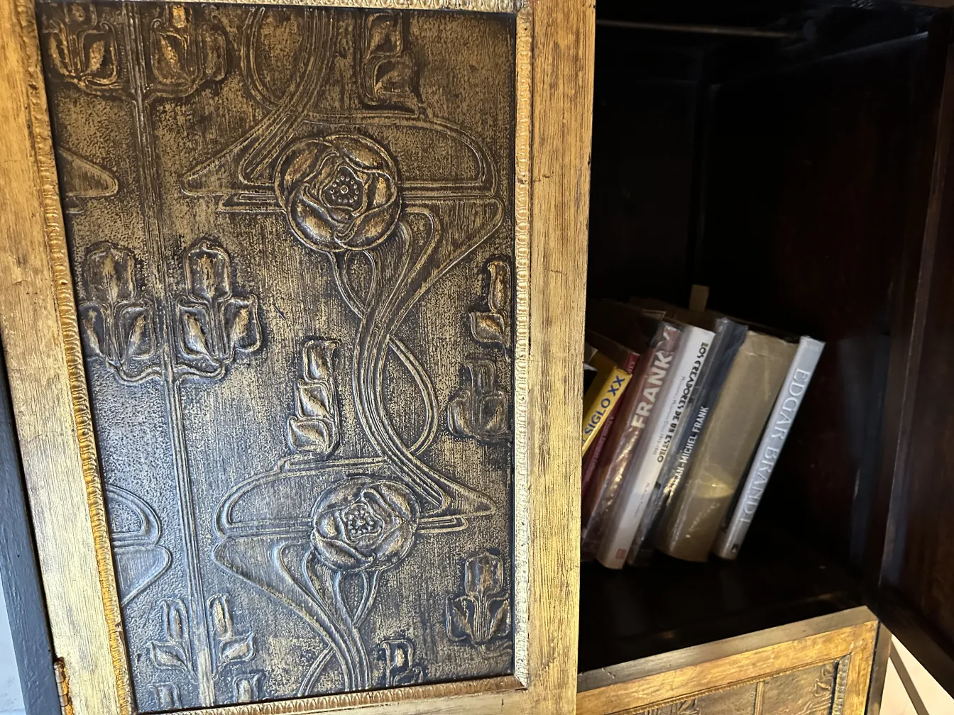 Meuble à cocktail ancien en bois avec détails en relief et livres à l'intérieur.