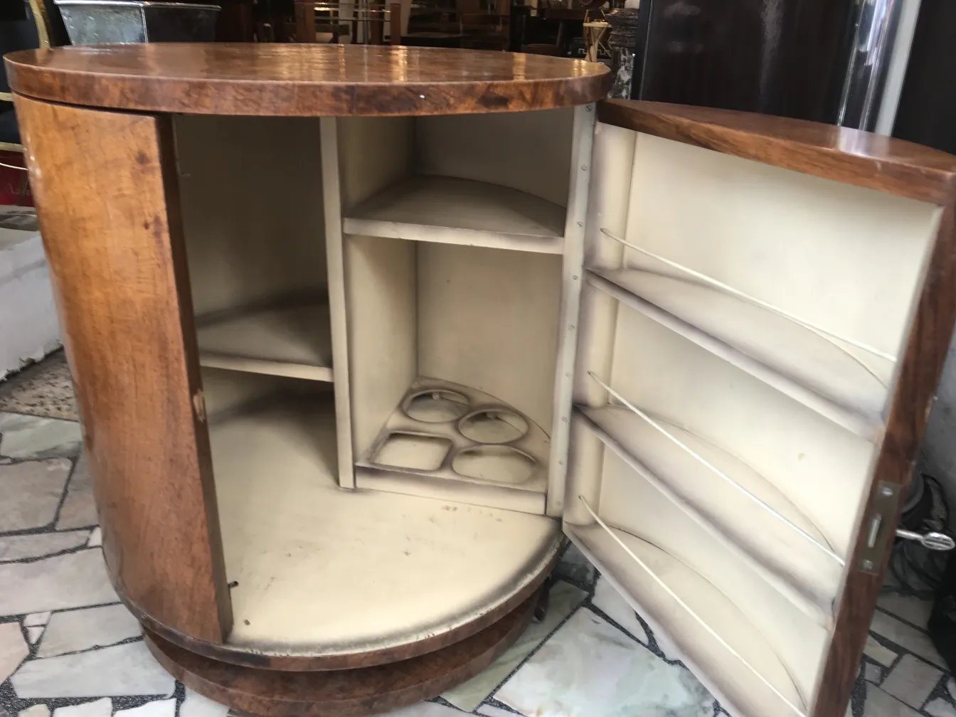 Mobile bar antico in legno con spazio di stoccaggio interno per bottiglie e bicchieri, situato in un ambiente vintage.