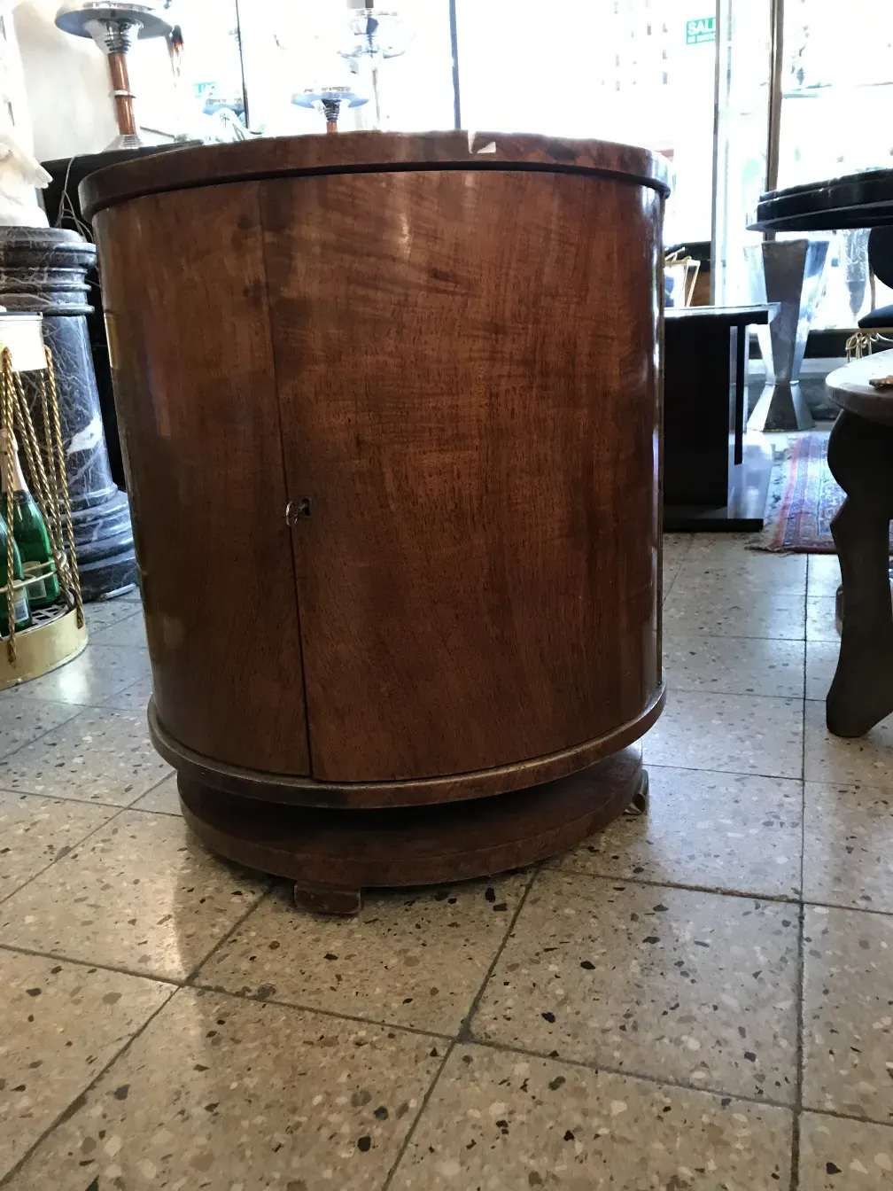 Mueble bar antiguo de madera, elegante y curvilíneo, en una tienda