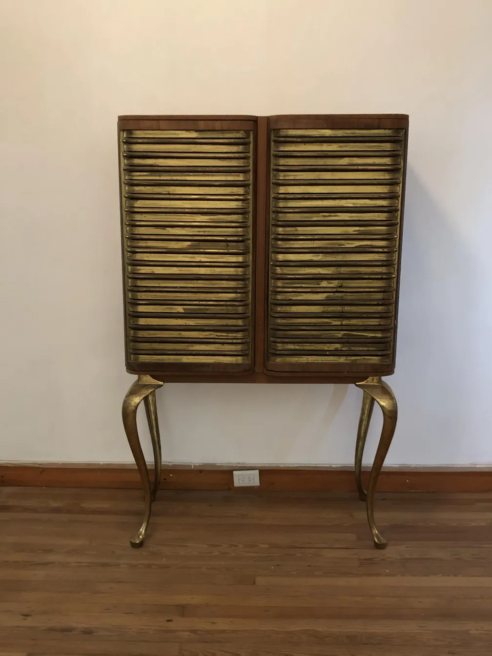 Meuble à cocktail ancien avec finition dorée et pieds stylés.