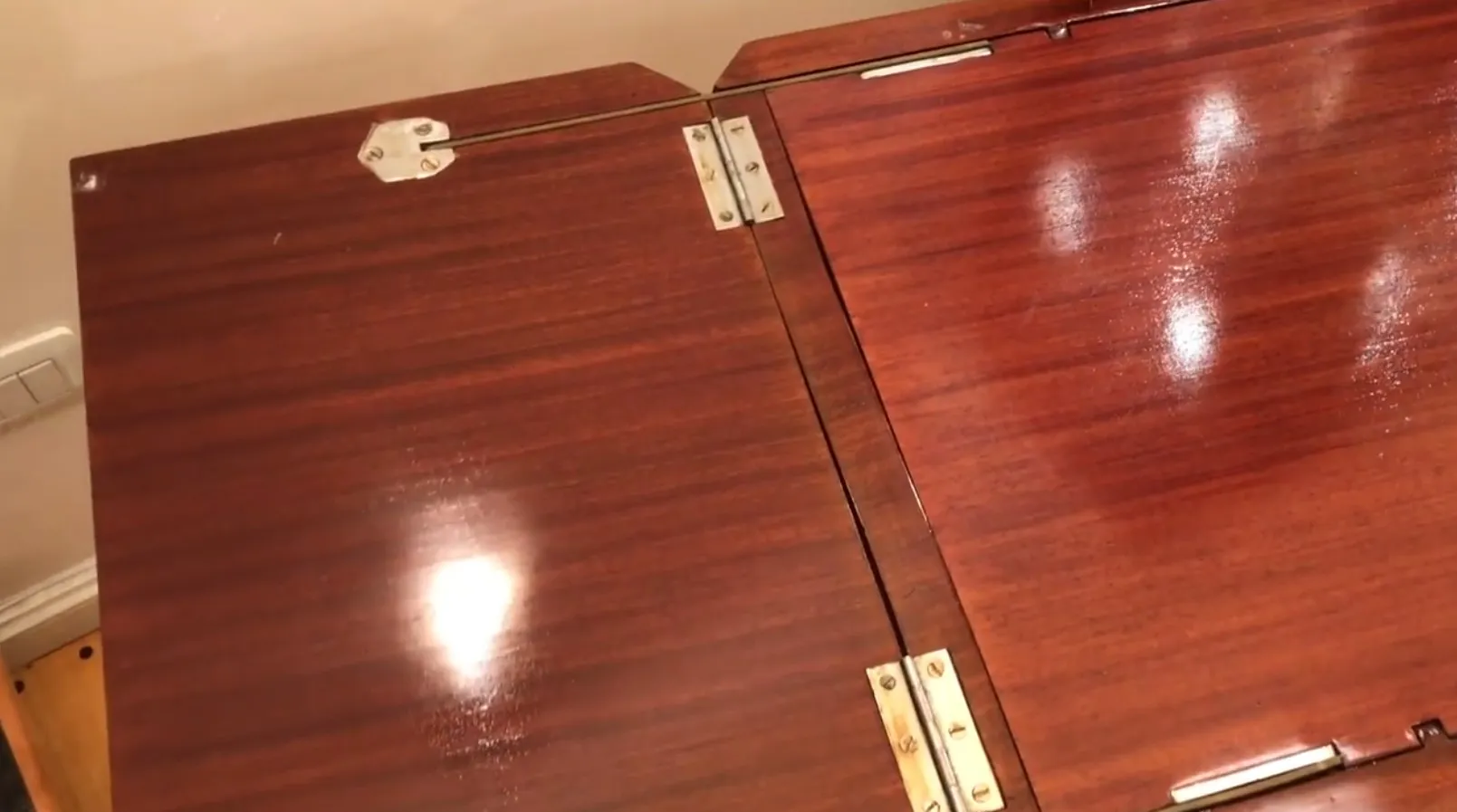 Antiker Cocktailschrank mit polierter Oberfläche und Metall-Scharnieren, in einem gemütlichen Ambiente.