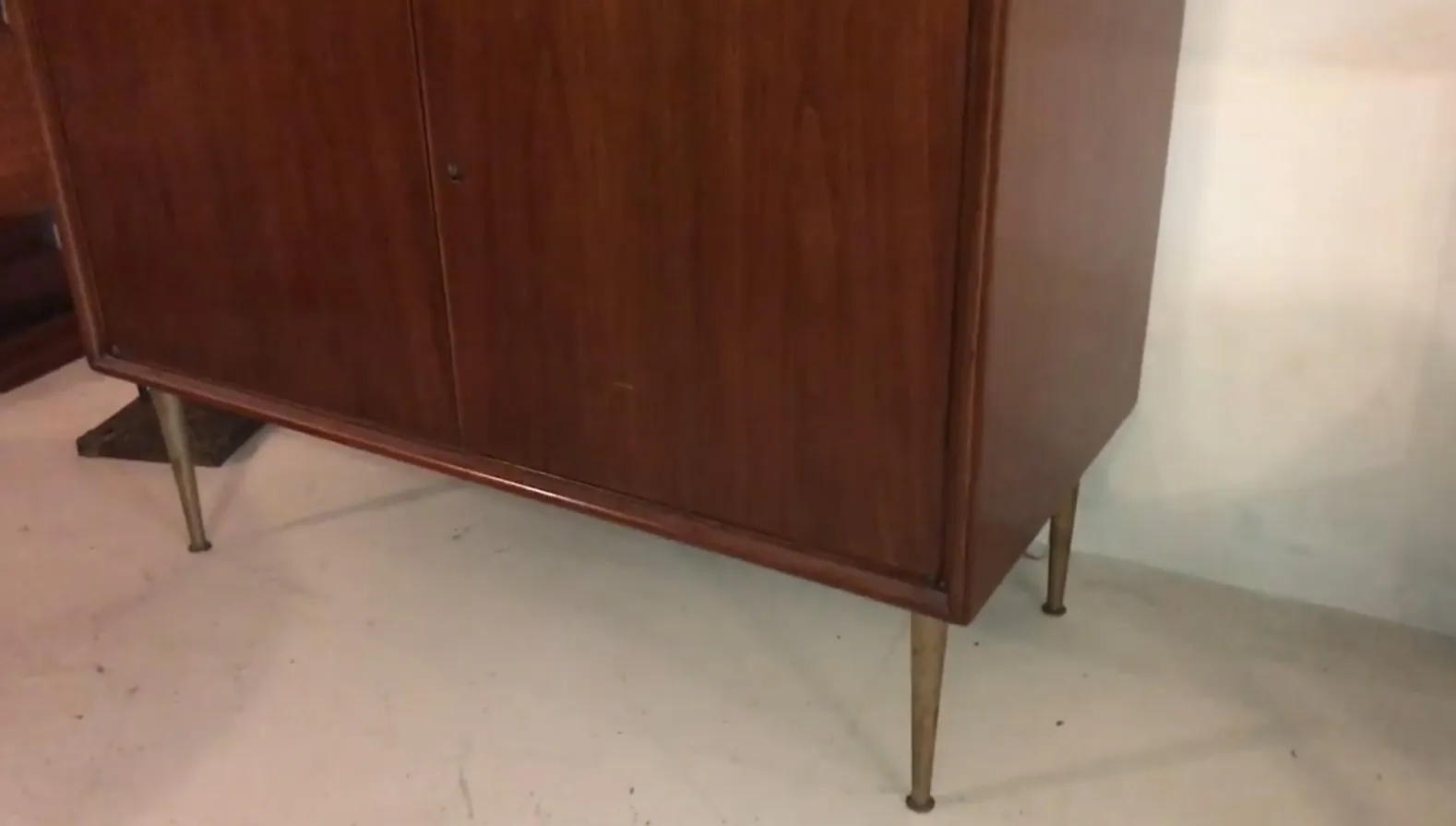 Mobile bar antico in legno con gambe eleganti in un ambiente classico.