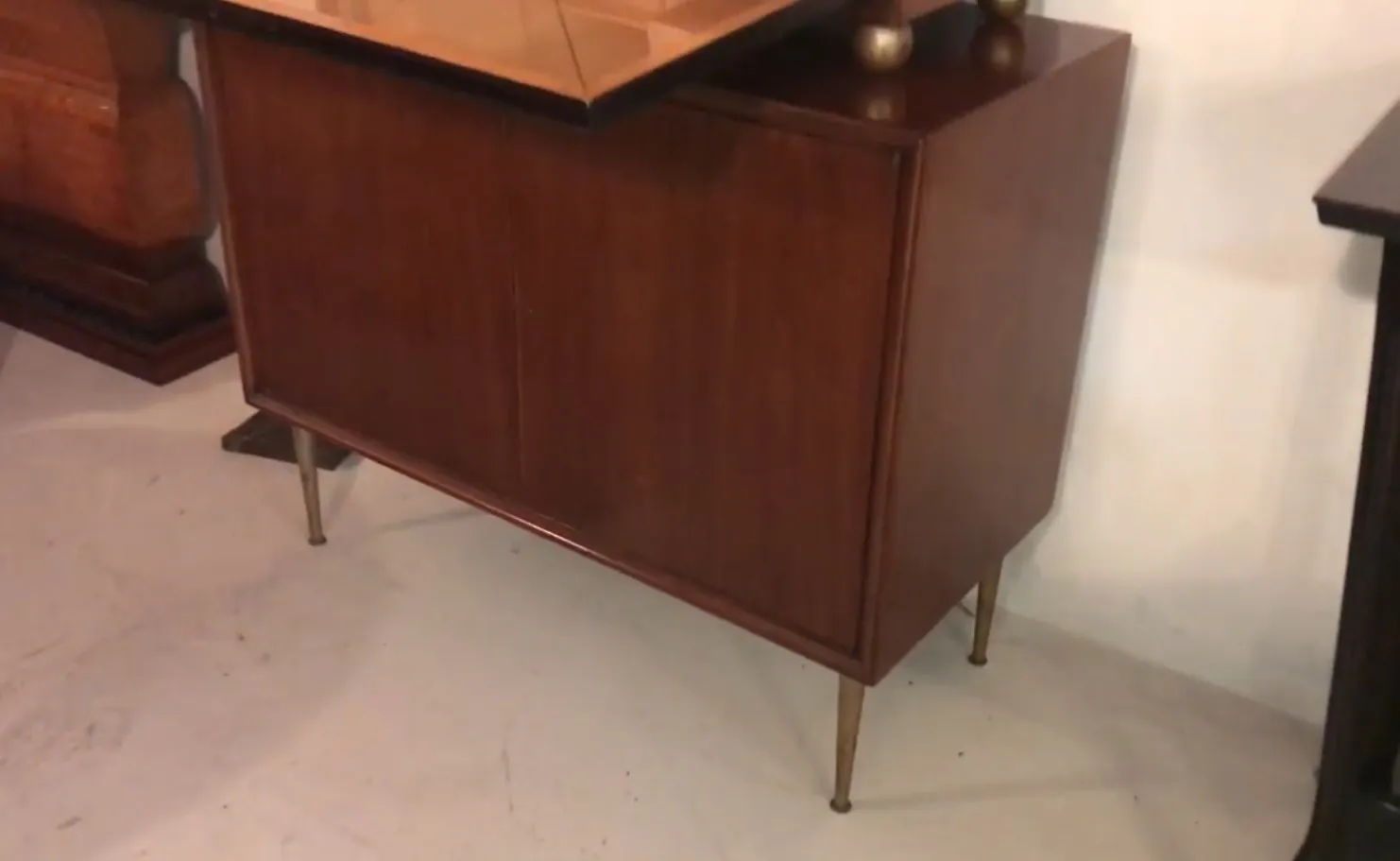 Mobile bar antico in legno con gambe dorate.