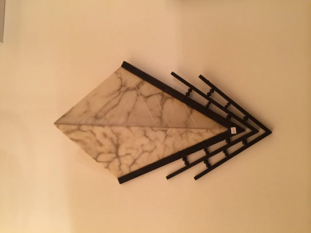 Antique pair of sconces with geometric shapes and marble details, mounted on a light-colored wall.