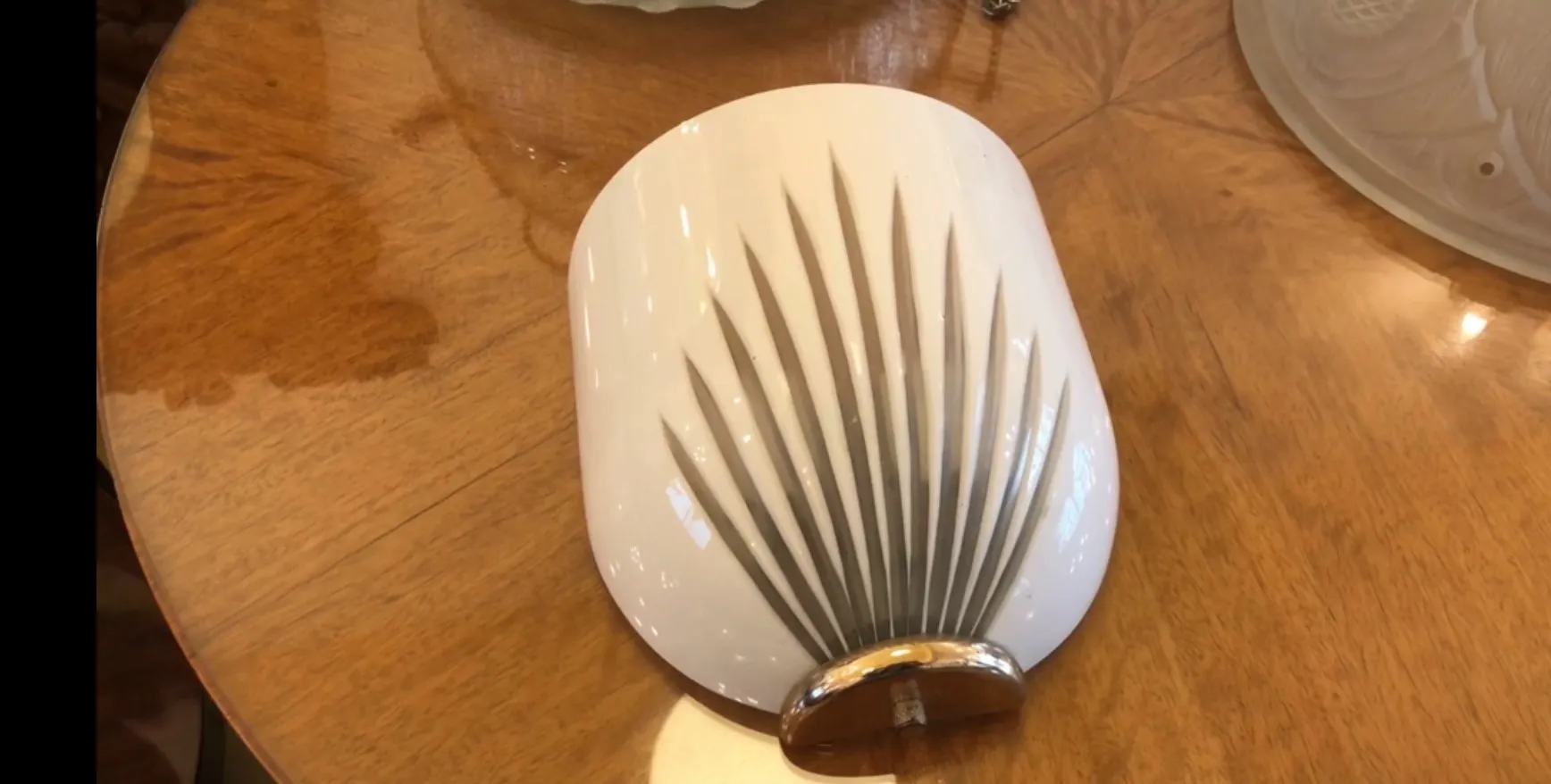 Paire d'appliques anciennes dans un style décoratif, blanches avec un design en relief, sur fond en bois.