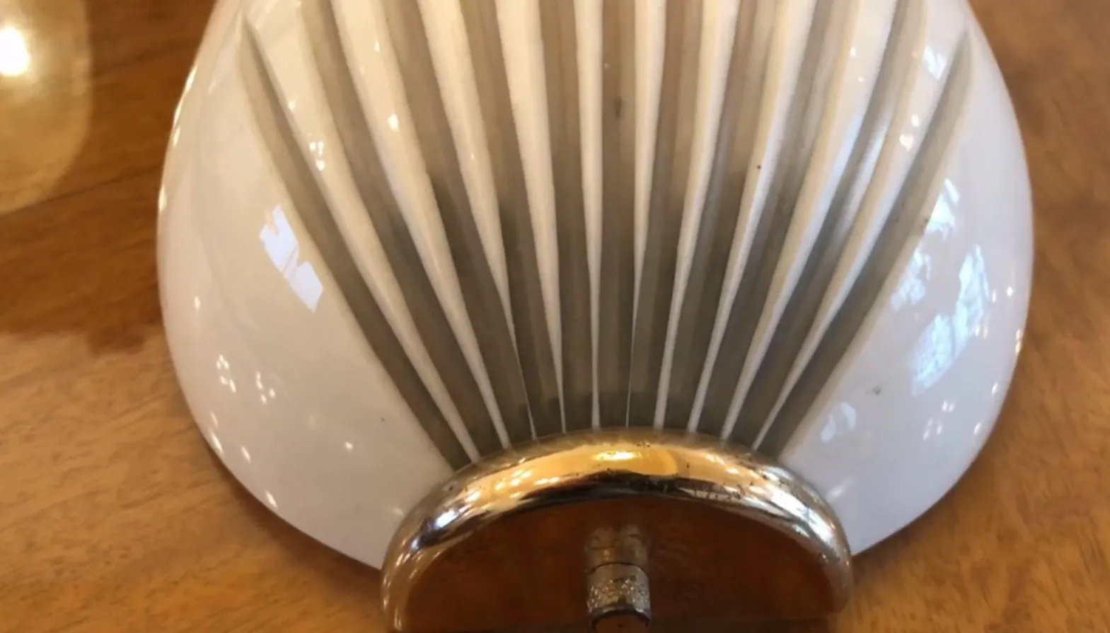 Par de luminárias de parede antigas com design elegante e acabamento brilhante, colocadas em uma superfície de madeira.