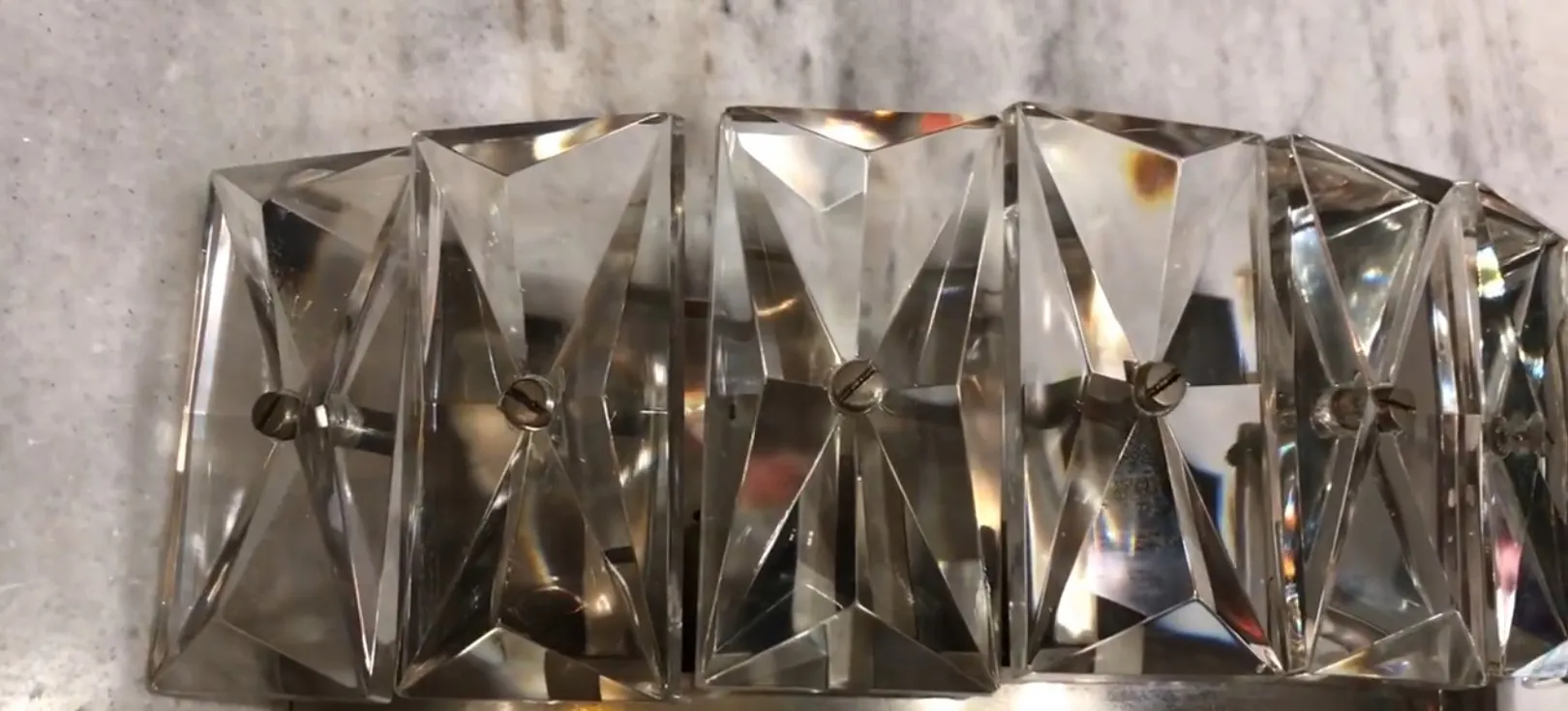 Par de luminárias de parede com design de vidro e metal em um fundo neutro