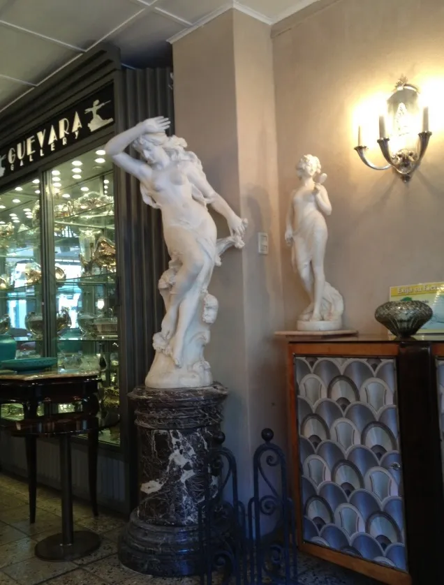 Par de apliques antiguos iluminando una escena con estatuas.