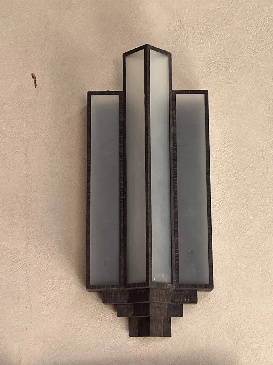 Antiguo par de apliques de pared iluminados, con un diseño elegante, sobre fondo claro.