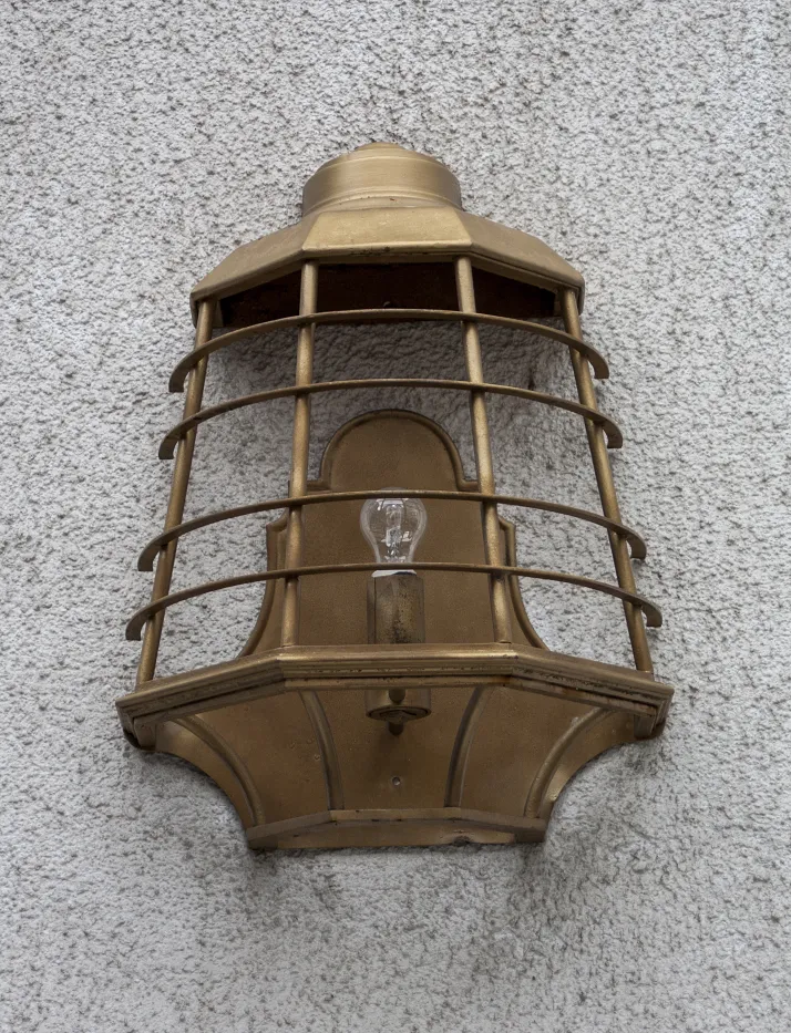 Antike goldene Wandleuchte an einer hellen Wand, stilvolle Dekoration.