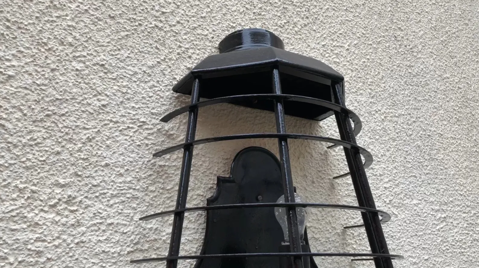 Antike Wandleuchter mit schwarzer Gittergestaltung.